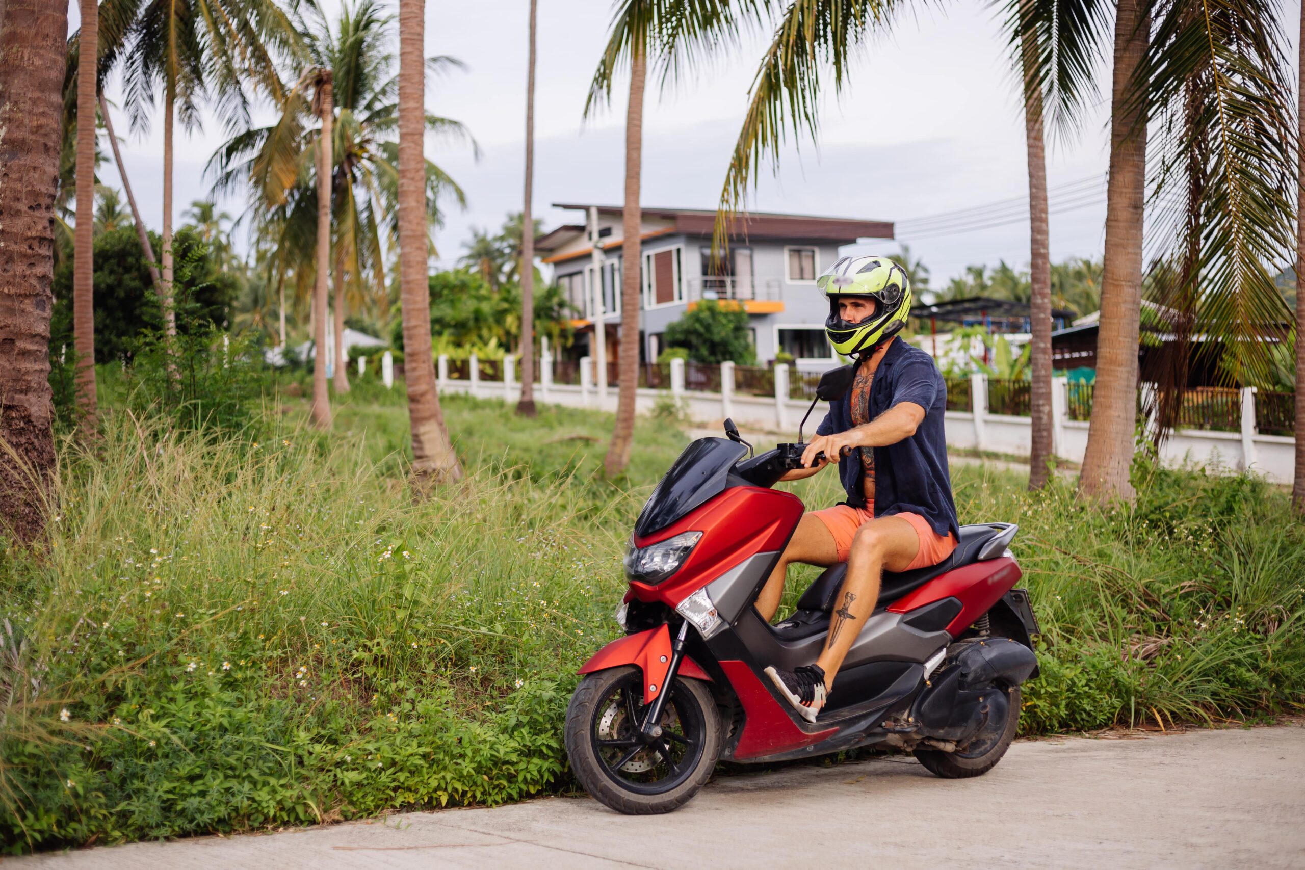 tattooed-strong-man-tropical-jungle-field-with-red-motorbike-min